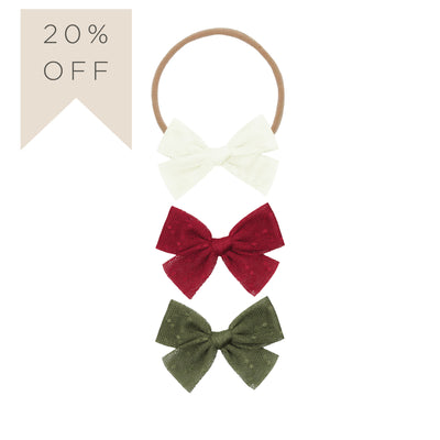 Three hair bows in red, green, and white on a beige background with a 20% off label.