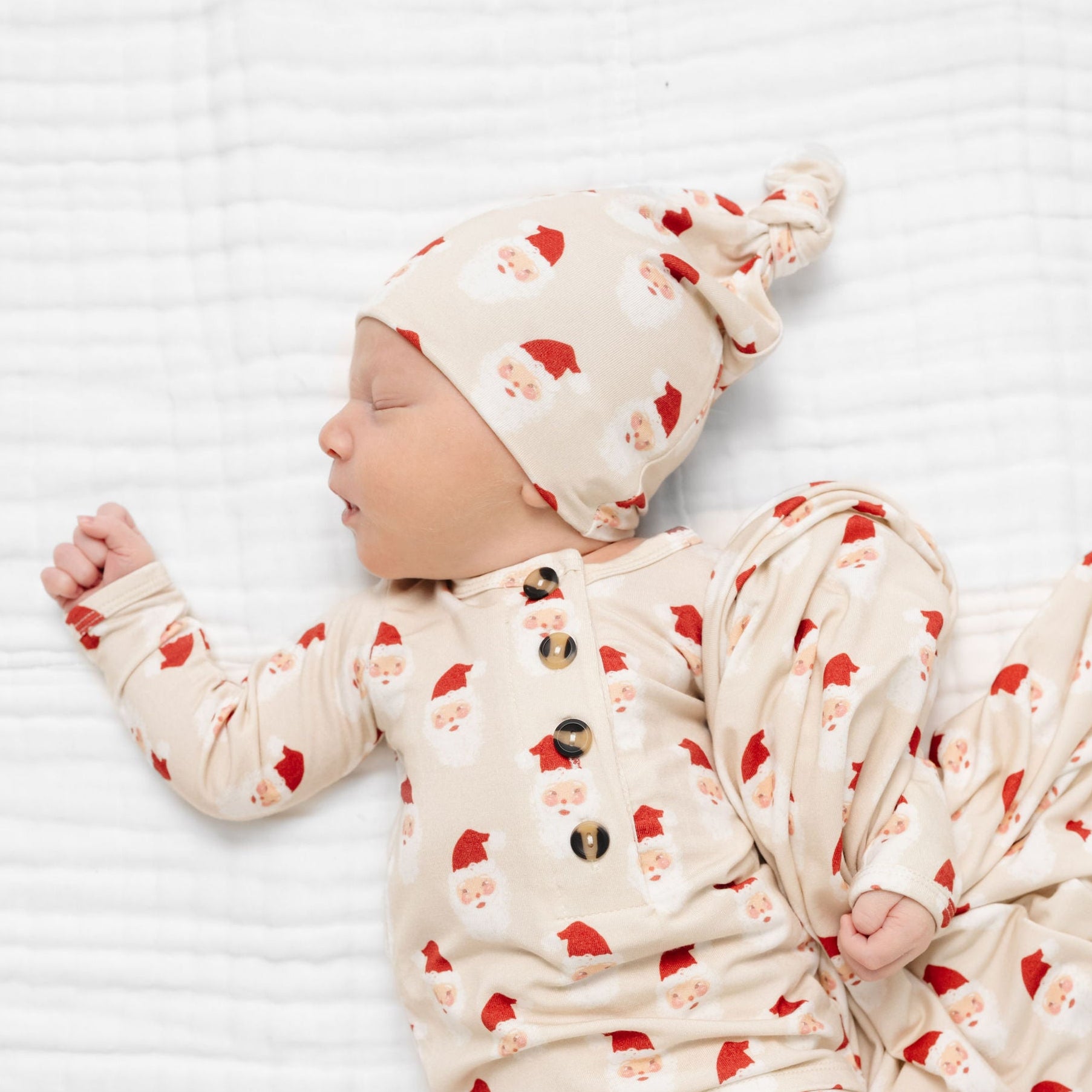 Newborn baby wrapped in a matching swaddle and hat with red heart patterns on a white background