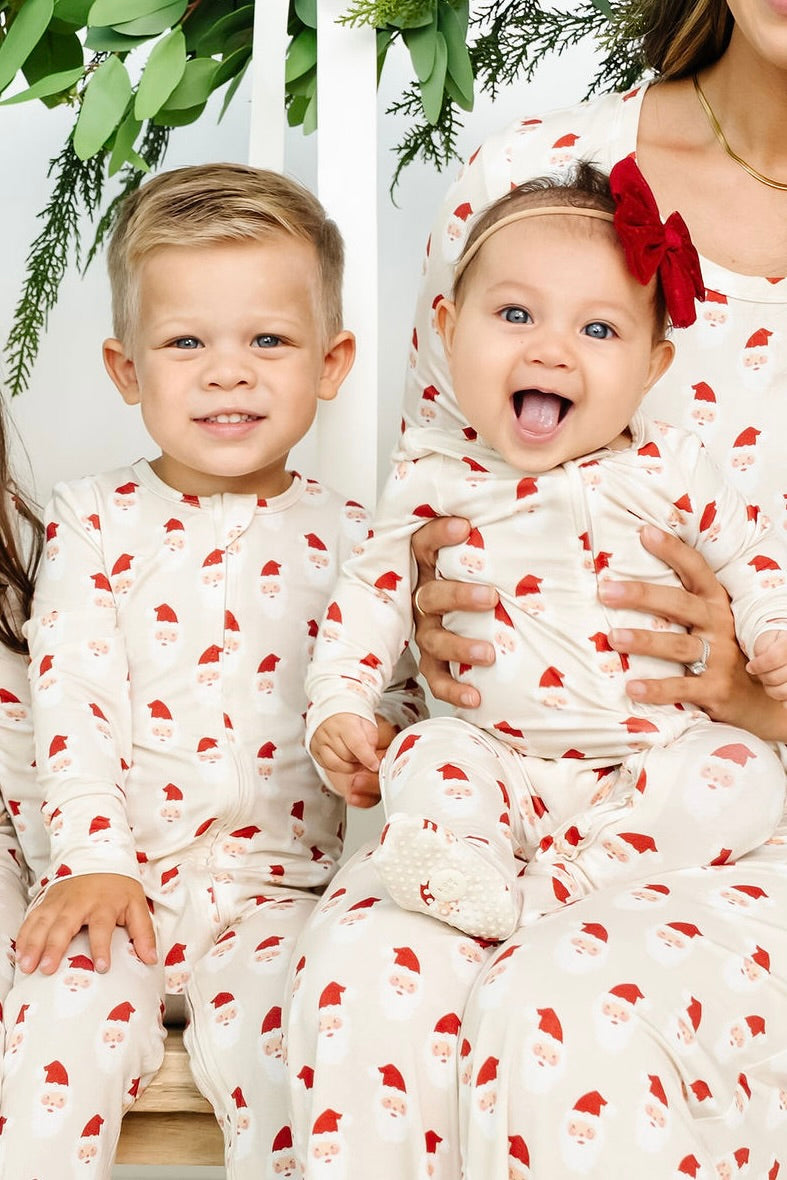 Two children in matching pajamas with a woman holding them, all wearing red bows.