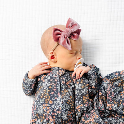 Baby in a floral outfit lying on a white textured surface