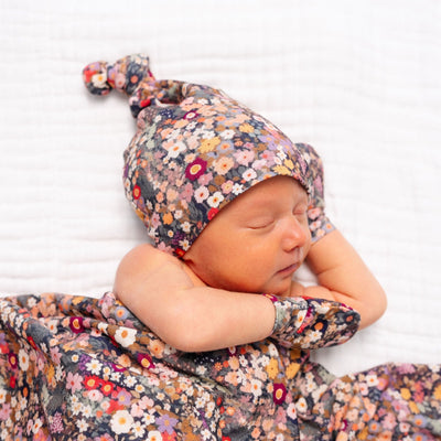 Newborn baby in a floral outfit and hat on a white background