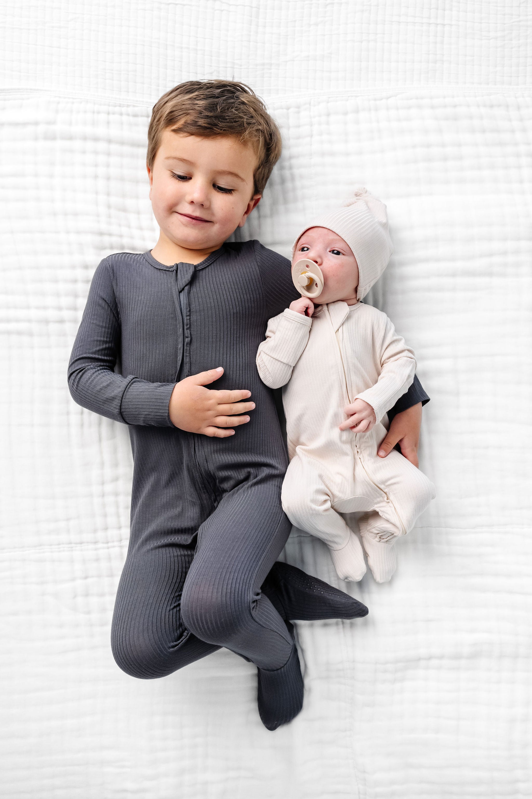 Hudson Zipper Footies toddler boy with baby brother laying on bed