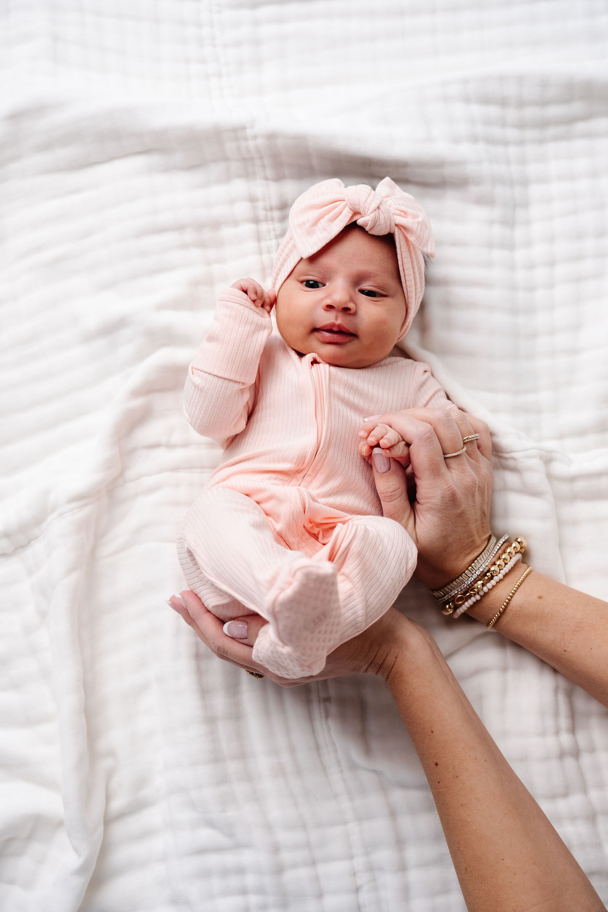 Rosie zipper footies baby girl in preemie size laying on bed with matching rosie headband