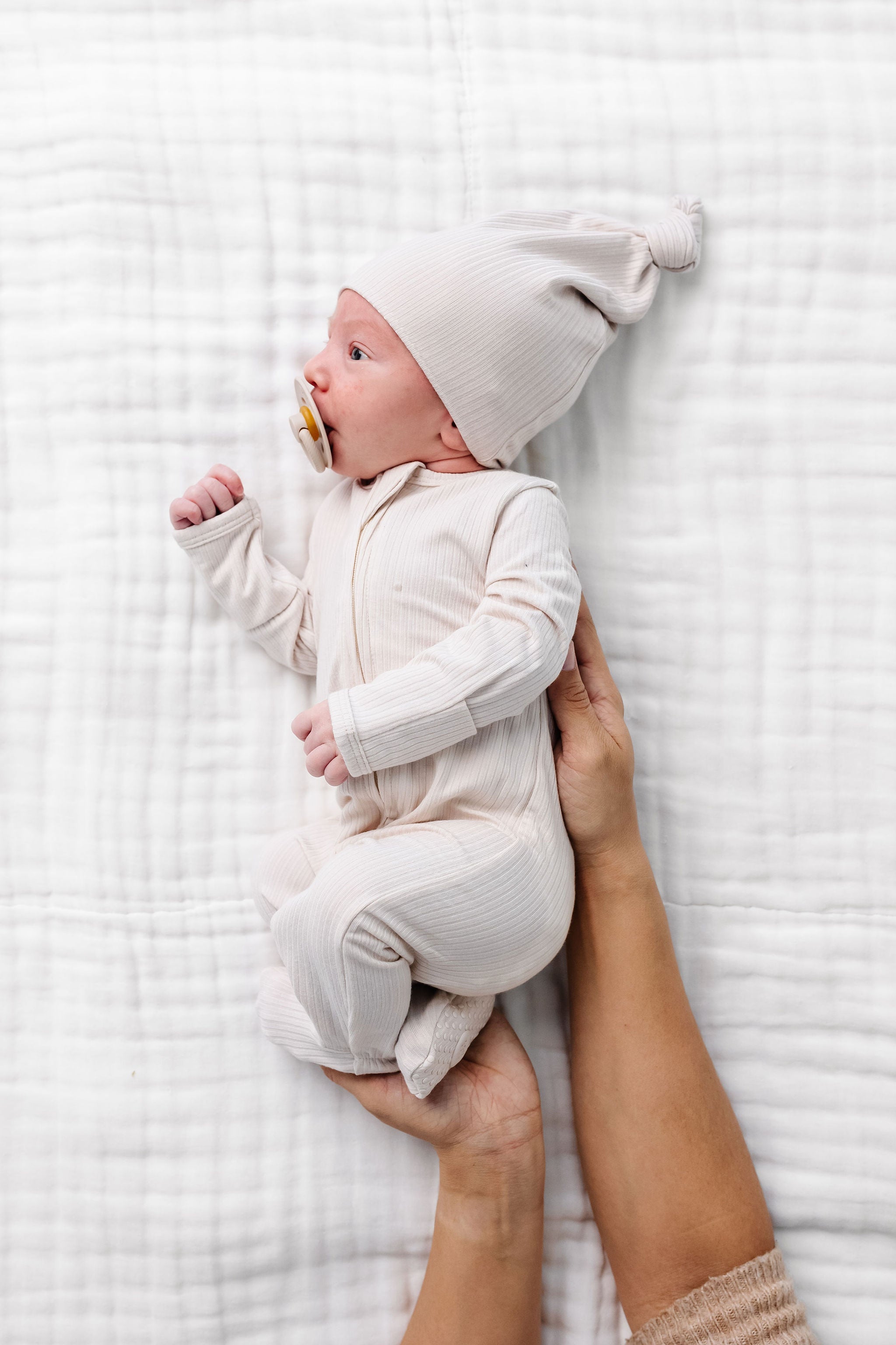 cove zipper footies newborn boy laying on bed