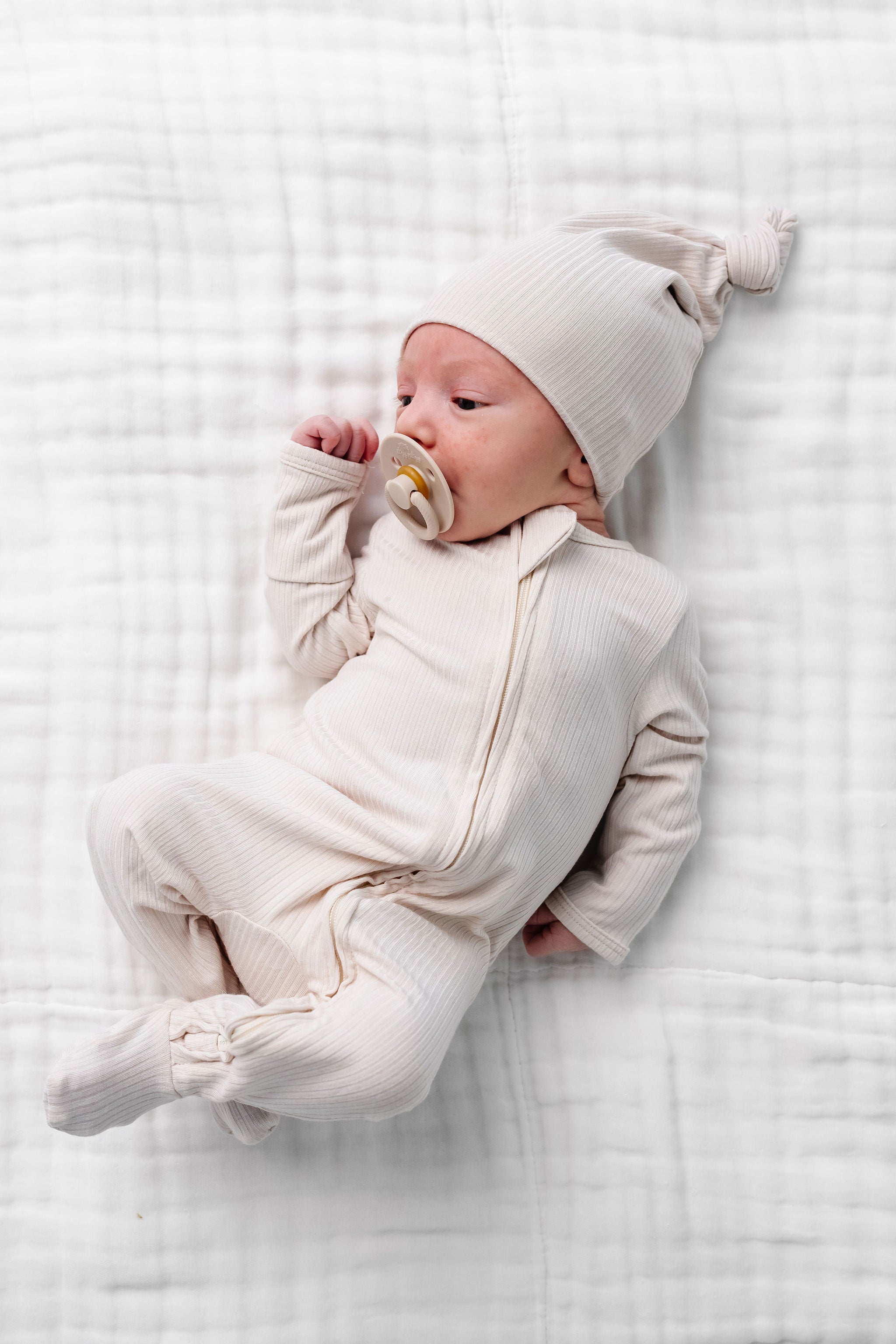 cove zipper footies newborn boy laying on bed
