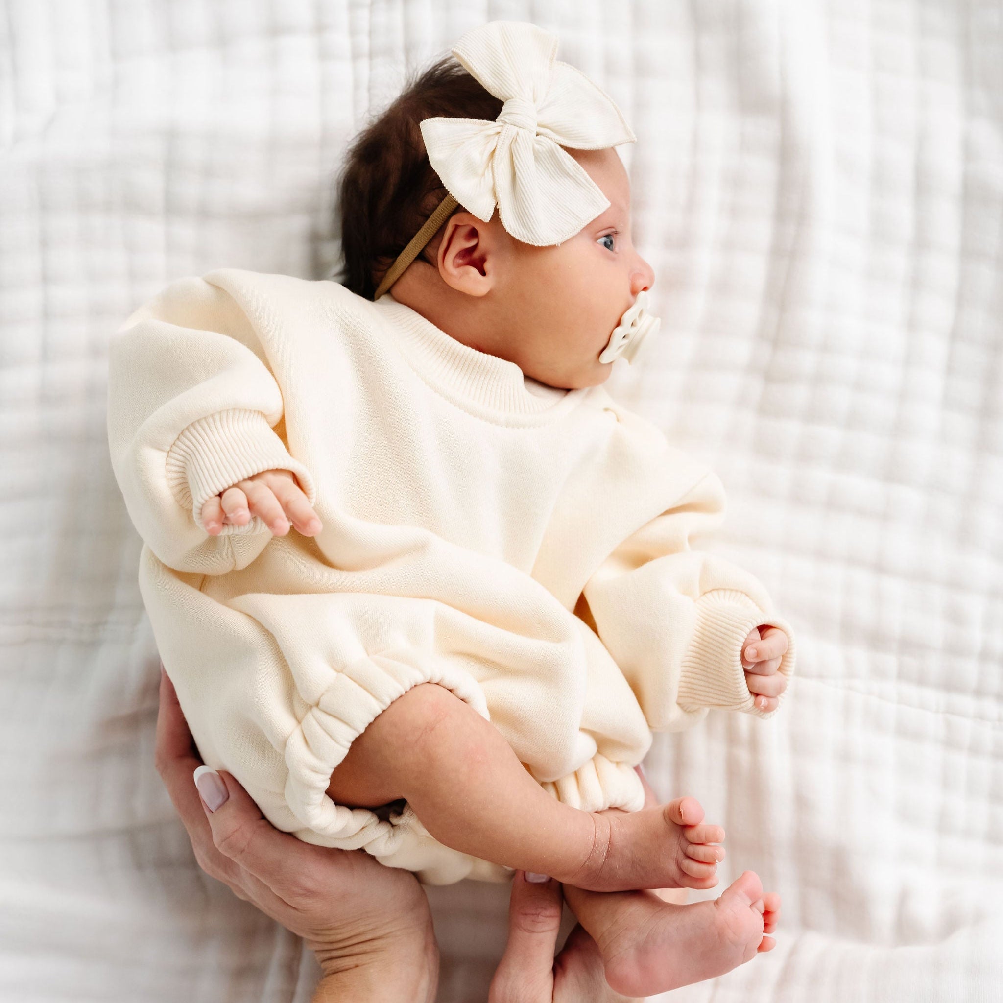 cream sweatshirt romper baby girl laying on bed