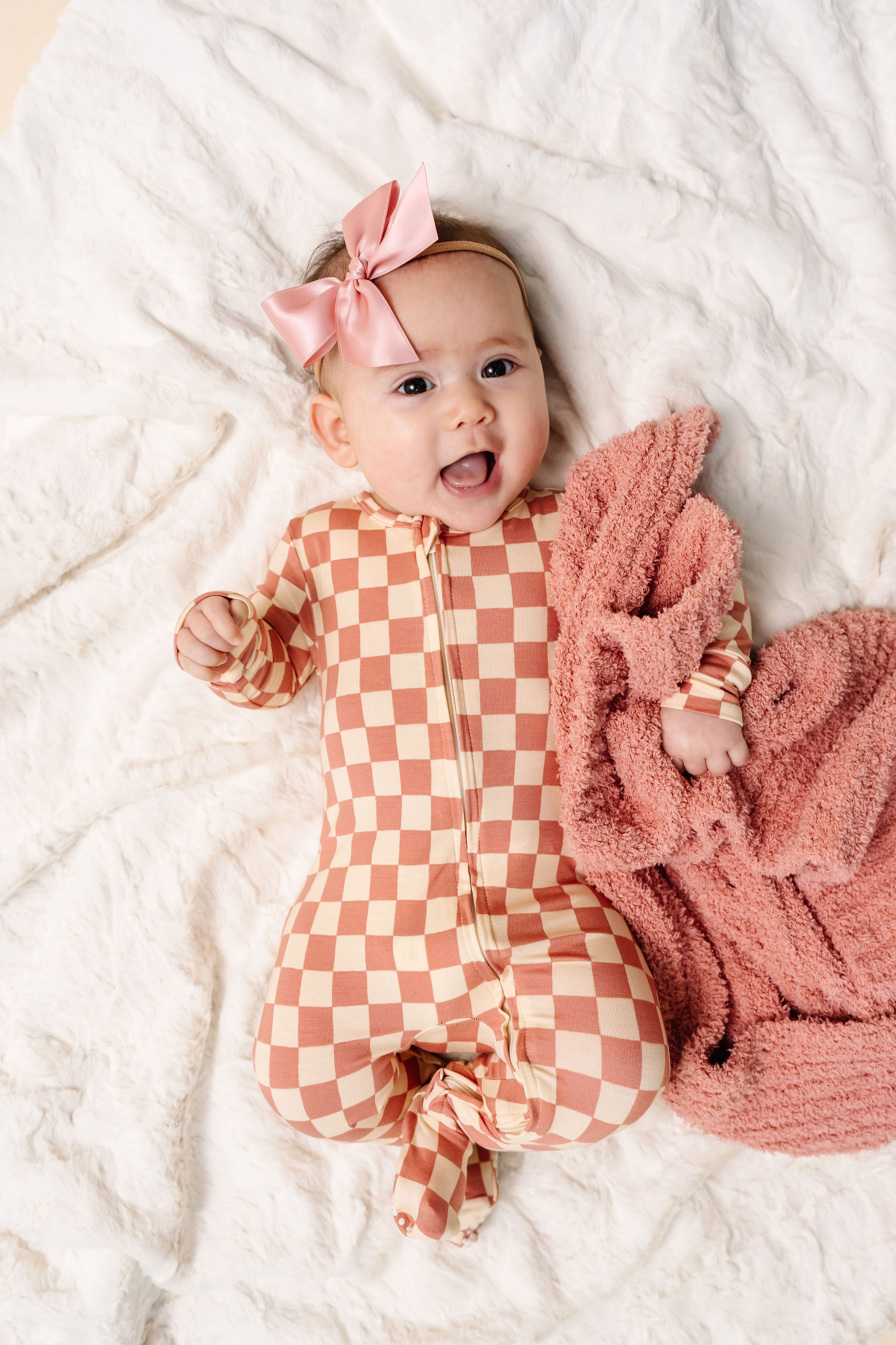 gemma zipper footies newborn girl laying on bed with rose chenille and french pink satin bow
