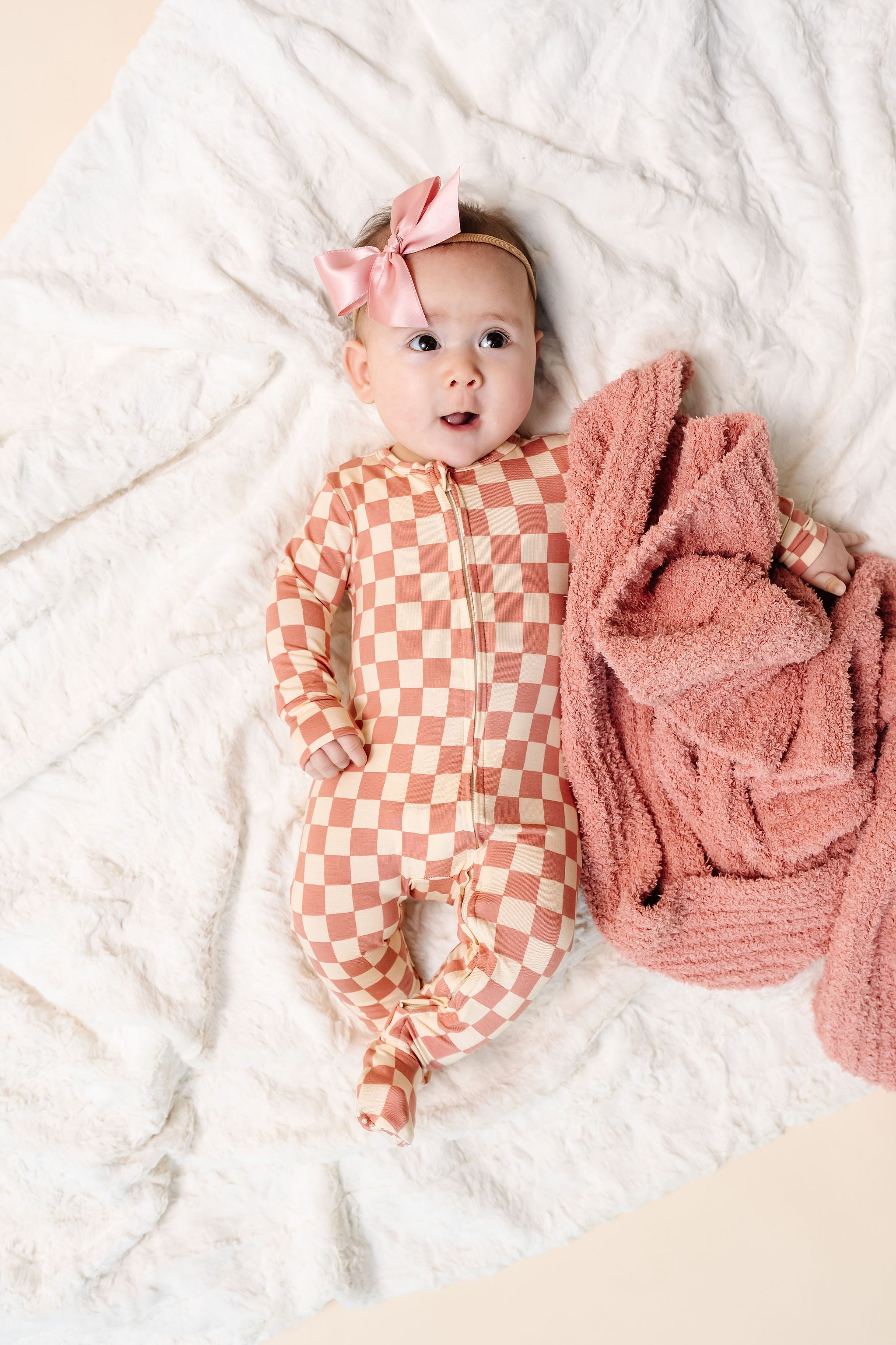gemma zipper footies newborn girl laying on bed with rose chenille and french pink satin bow