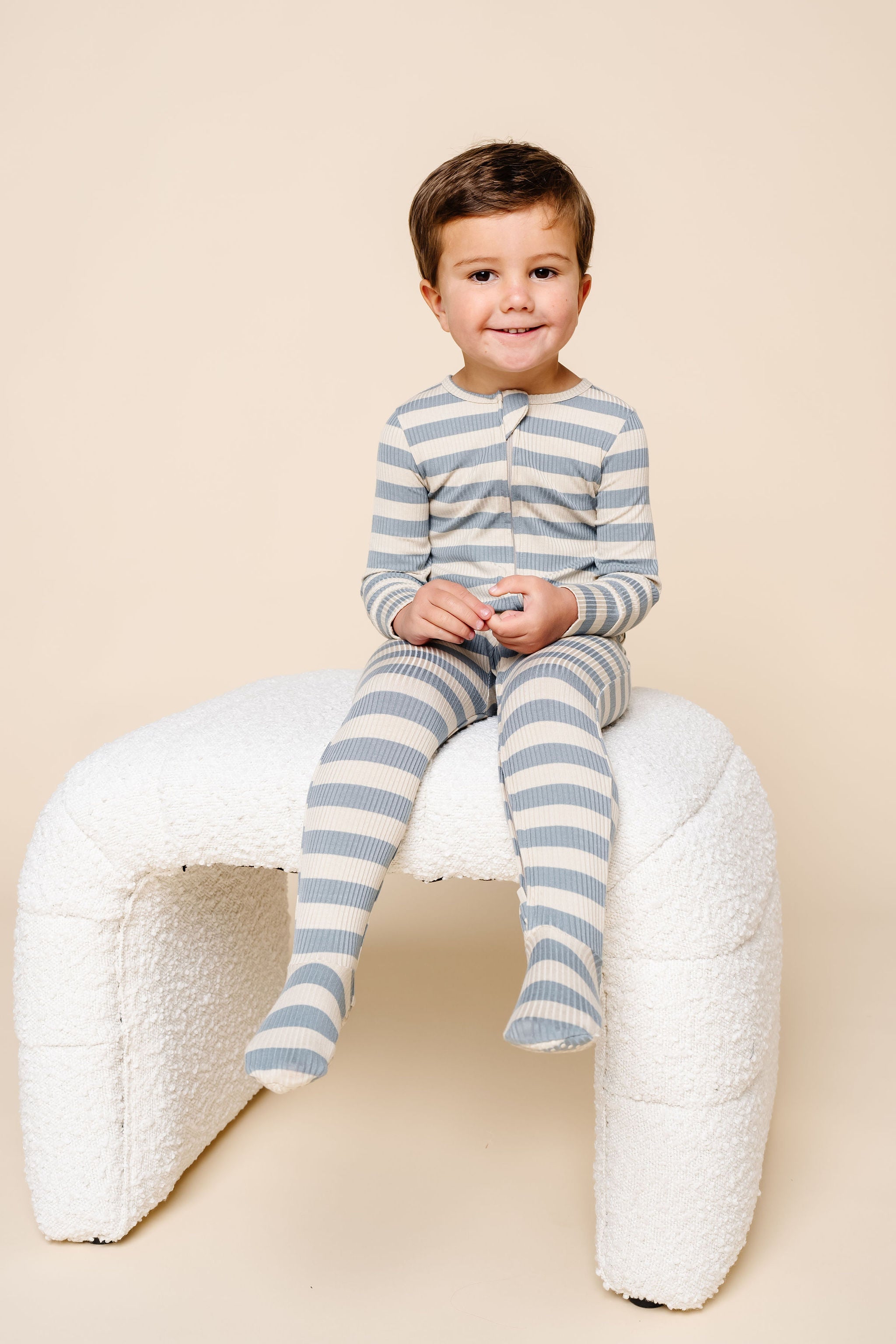 lincoln zipper footies toddler boy sitting on stool.