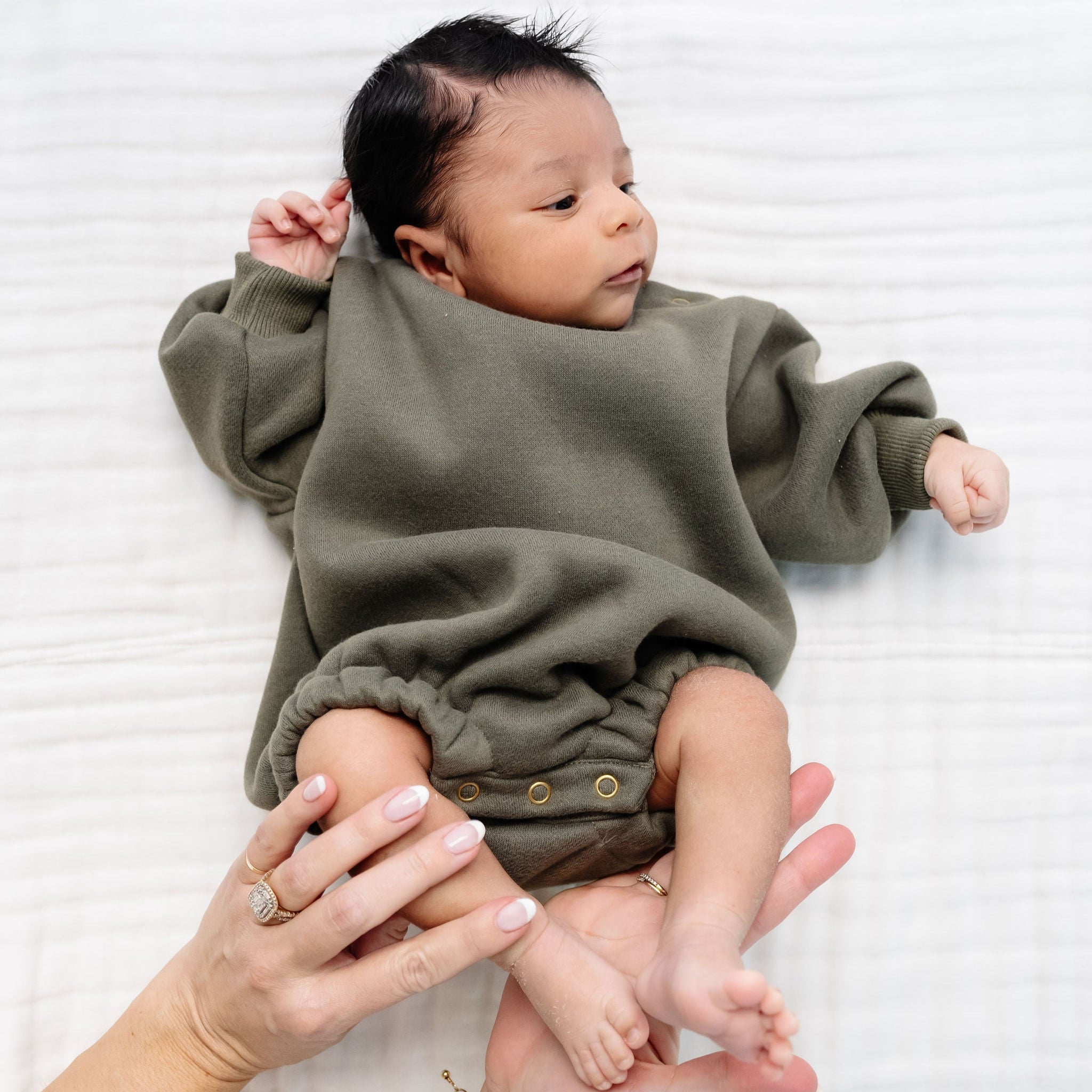 olive sweatshirt romper newborn baby boy laying on bed