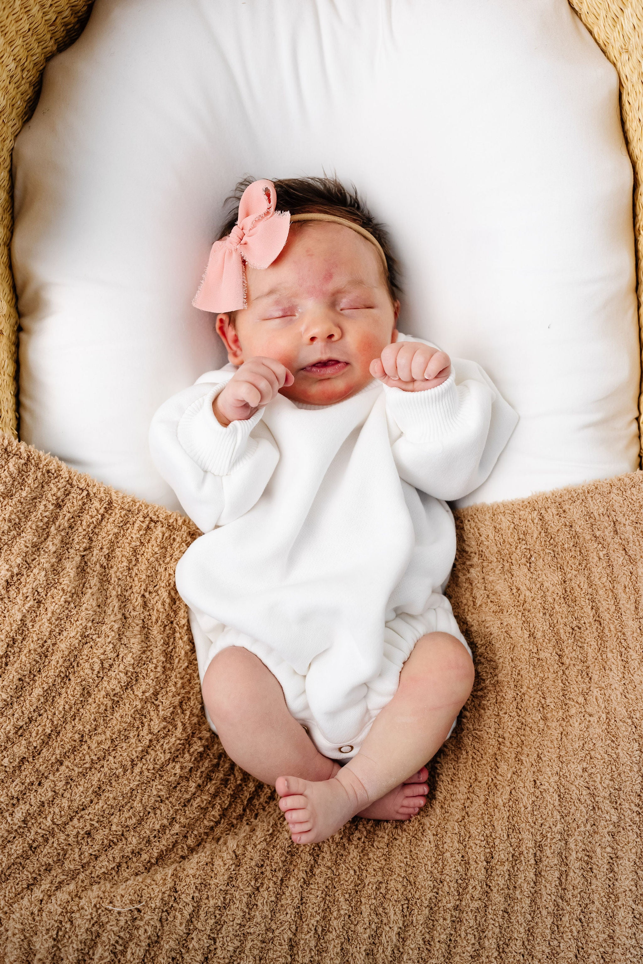 white sweatshirt romper baby girl laying in moses basket