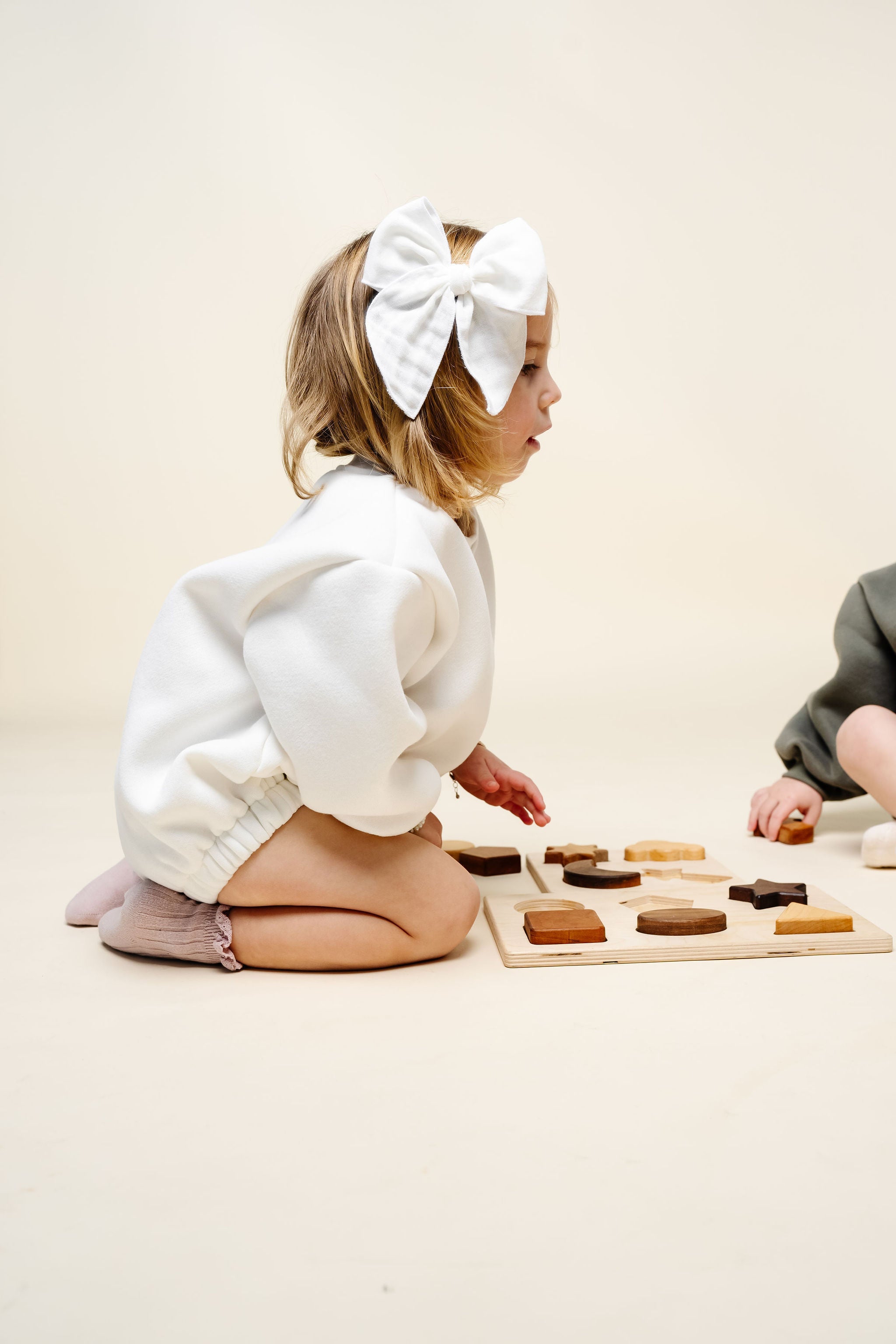 white sweatshirt romper nellie toddler girl playing with toys
