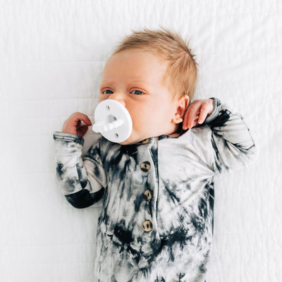 Baby in a tie-dye onesie lying on a white surface