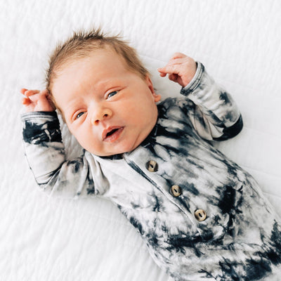 Newborn baby wearing a tie-dye outfit on a white blanket