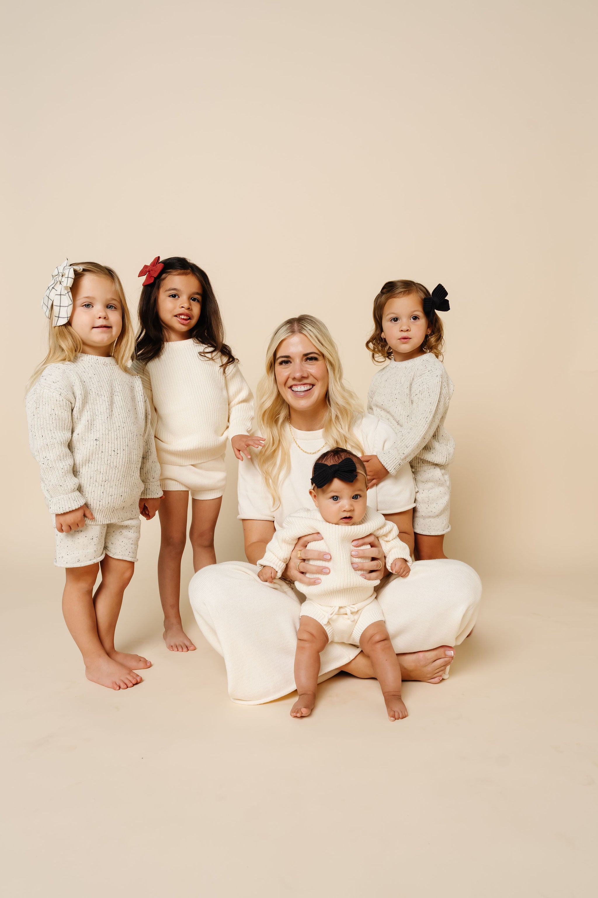 Woman with four children in matching outfits on a beige background