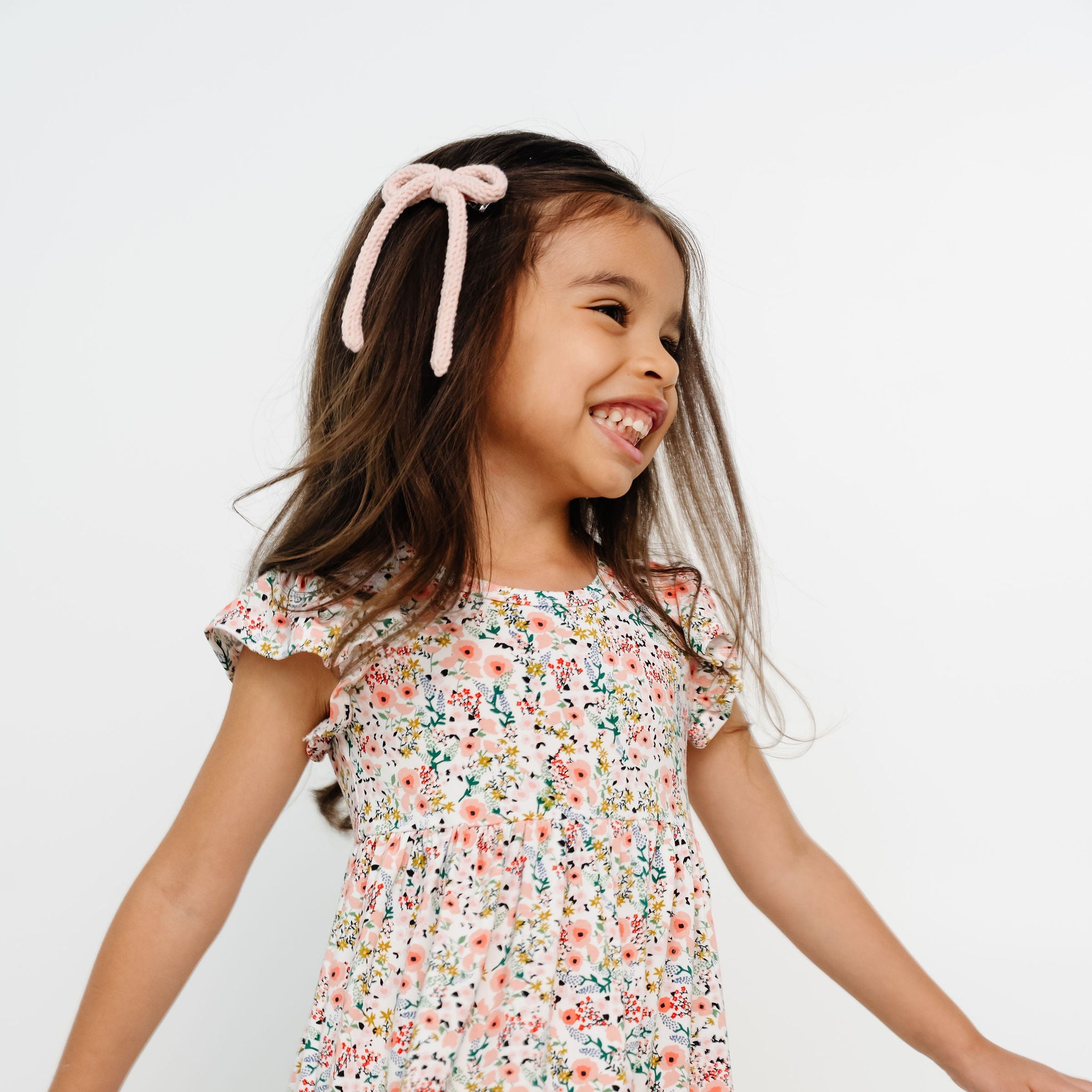 Young girl wearing a floral dress with a white background