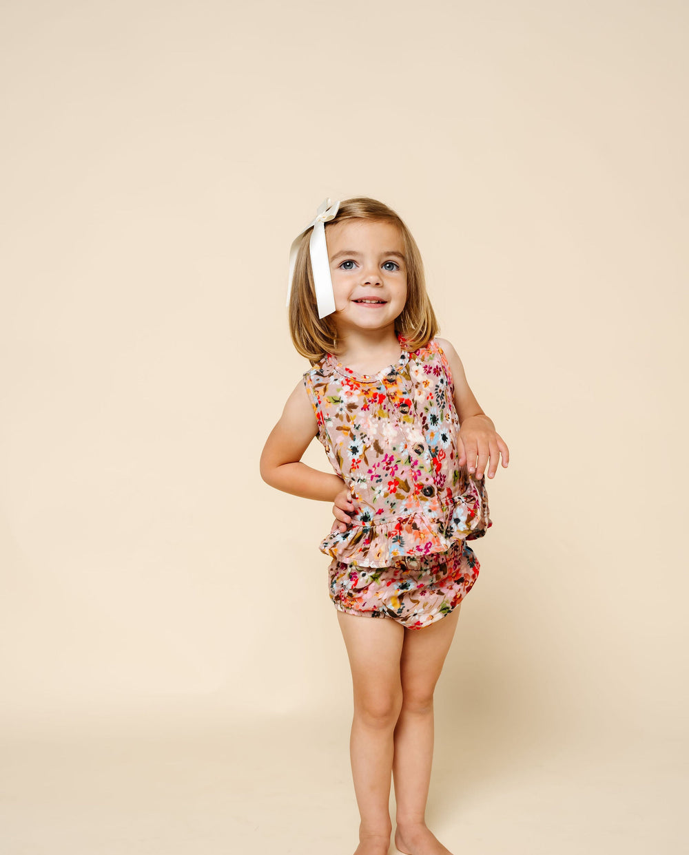 Young girl wearing a floral dress against a beige background