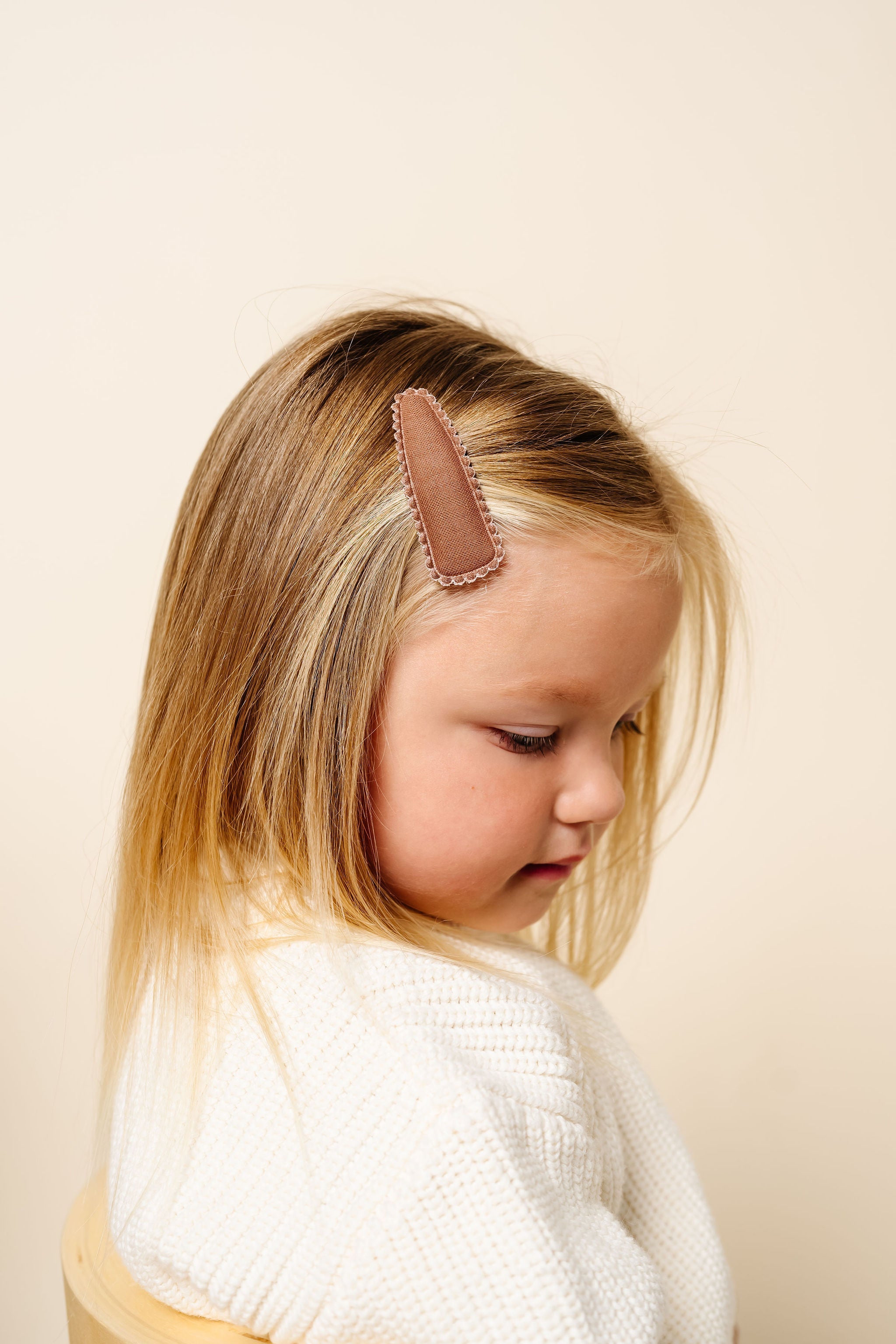 Child wearing a brown headband against a beige background