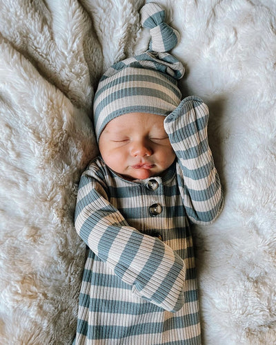 baby boy in lincoln gown and top knot hat laying on a blanket