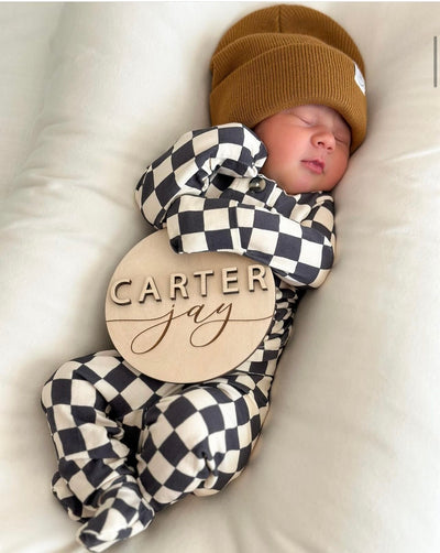 Newborn boy in gibson newborn top and bottoms with a camel beanie with a carter jay name sign. 