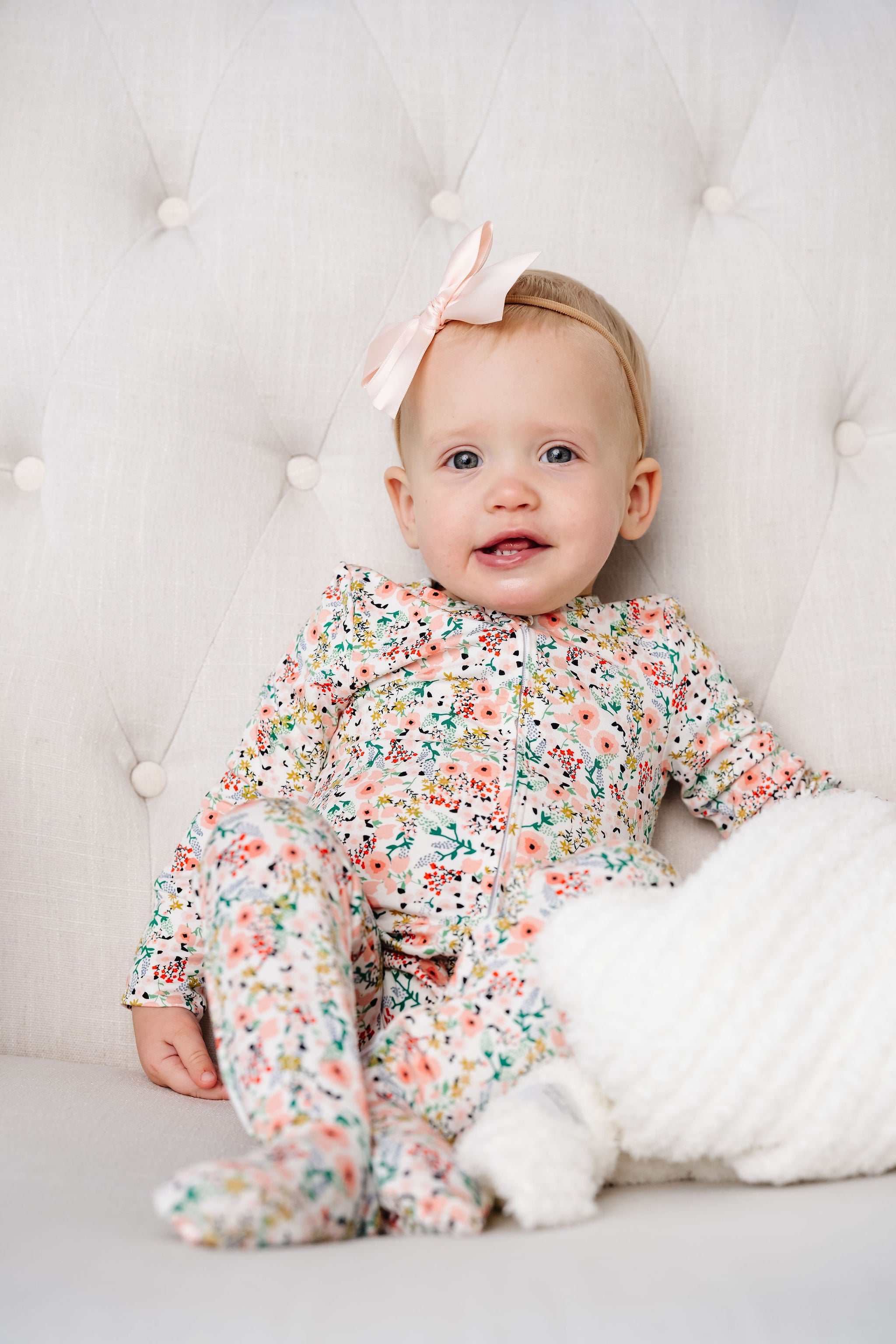 Millie Zipper Footies baby girl in 6-12 month size sitting in chair with blush satin bow 