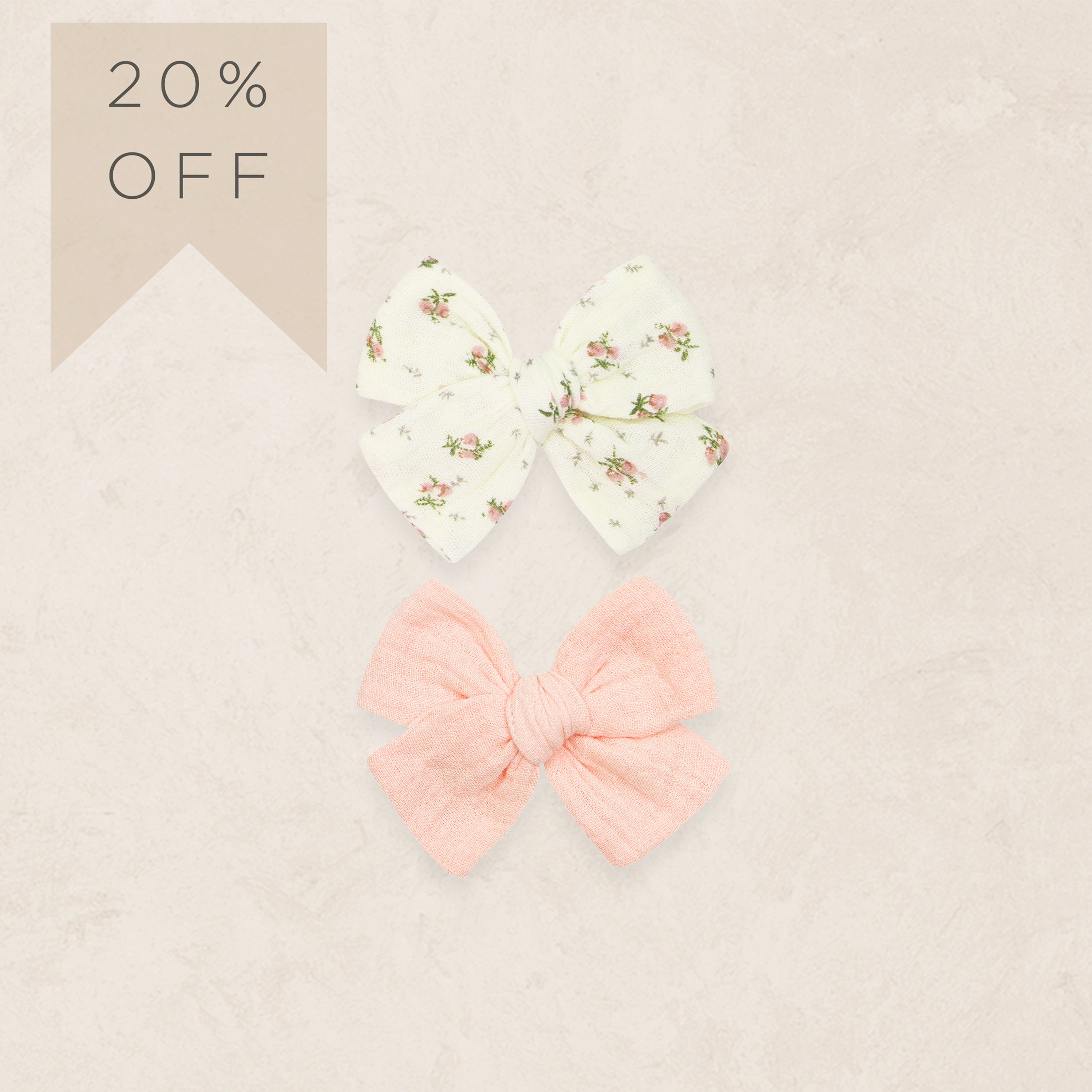 Two hair bows, one floral and one pink, on a beige background with a '20% OFF' label.
