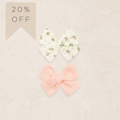 Two hair bows, one floral and one pink, on a beige background with a '20% OFF' label.